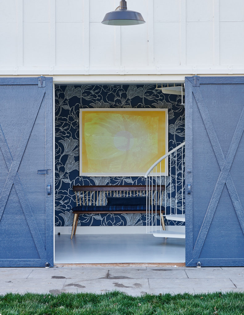 In a coastal home, a pair of barn doors are painted glossy cobalt. Wallpaper is Farrow & Ball. (Photo Amy Neunsinger)