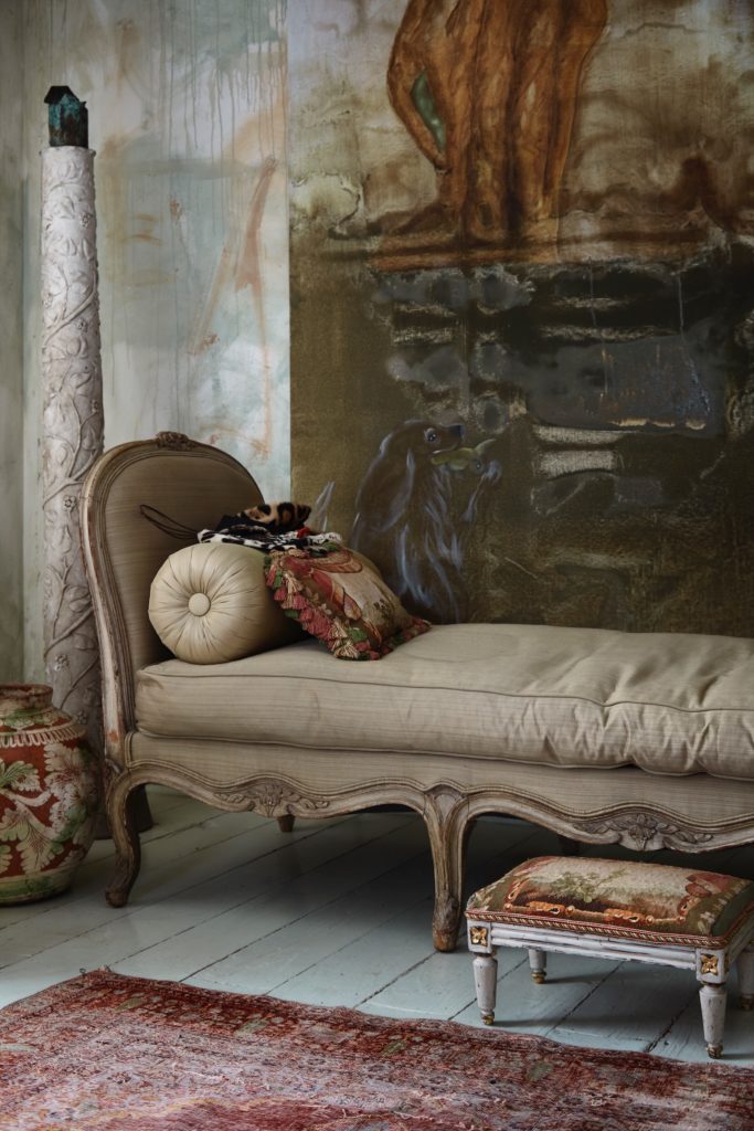 A painting by Werner-Vaughn is a backdrop for an 18th-century French daybed and 19th-century chair in original tattered condition. A footstool reupholstered in antique tapestry. (Photo by Lisa Petrole, Art Direction by Michelle Aviña)