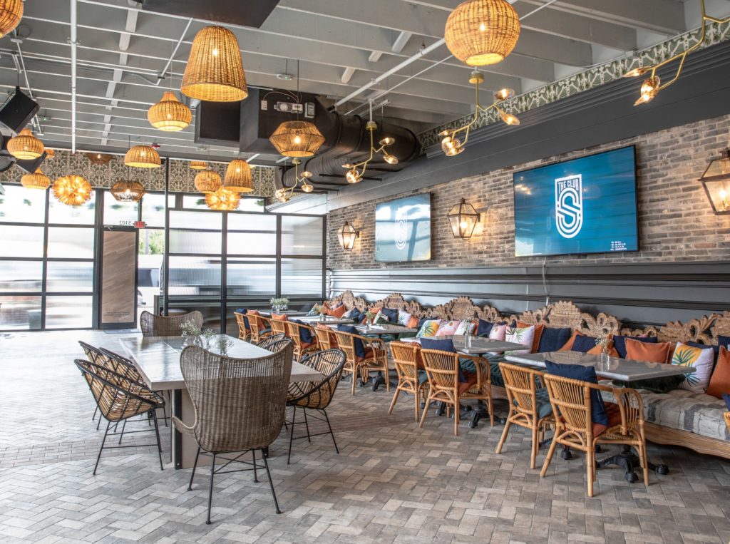 Rustic brick walls highlight the rattan furnishings and creative lighting sourced  from Restoration Hardware, Article and others. (Photo by Corine Michel )