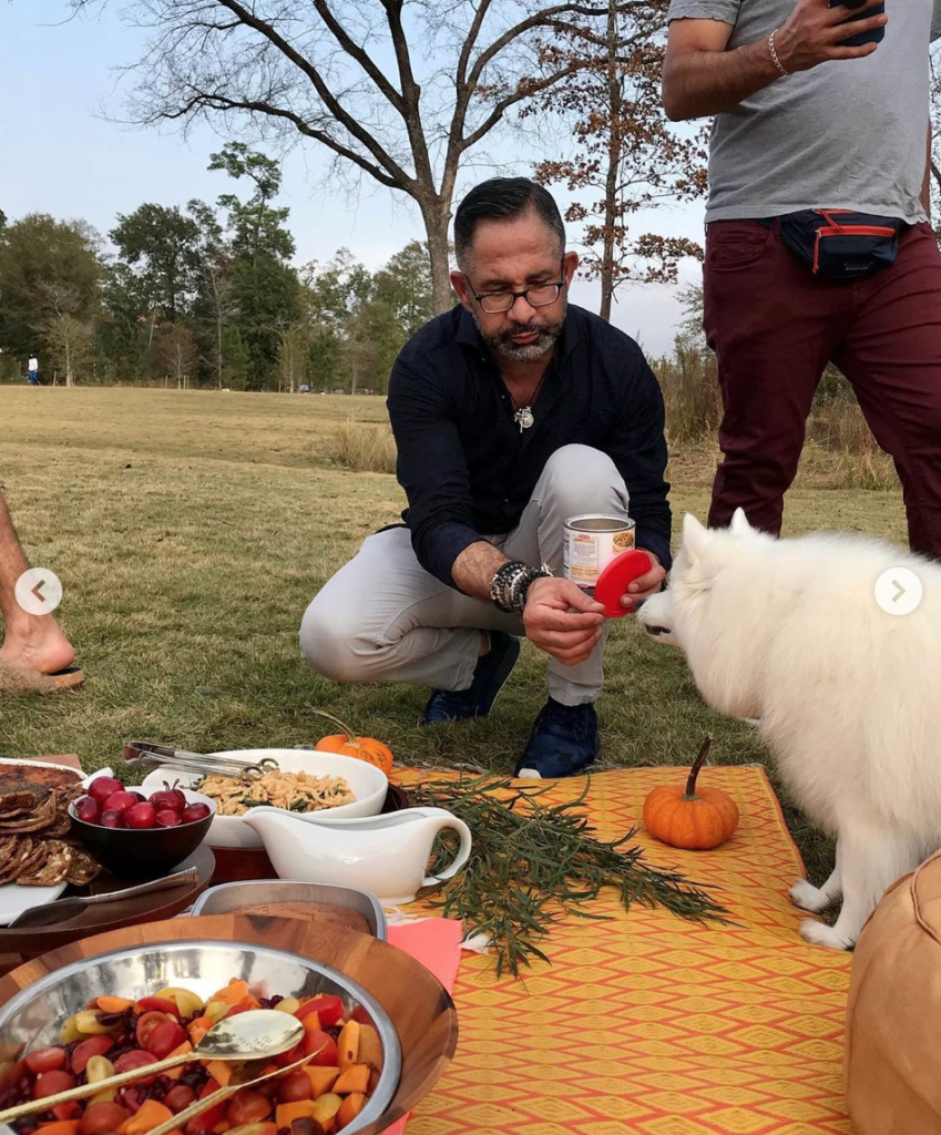 A four-legged friend joins Calvin Azzam and others at the Thanksgiving Day picnic in the Clay Family Eastern Glades in Memorial Park.
