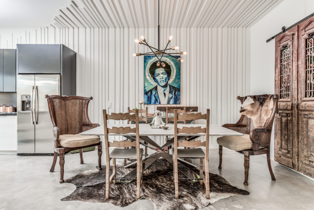 In this Nouveau Bungalow, the Steven Allen Designs features a raised texture accent wall that gives a contrast from the dining room to the kitchen mixed with vintage furniture.