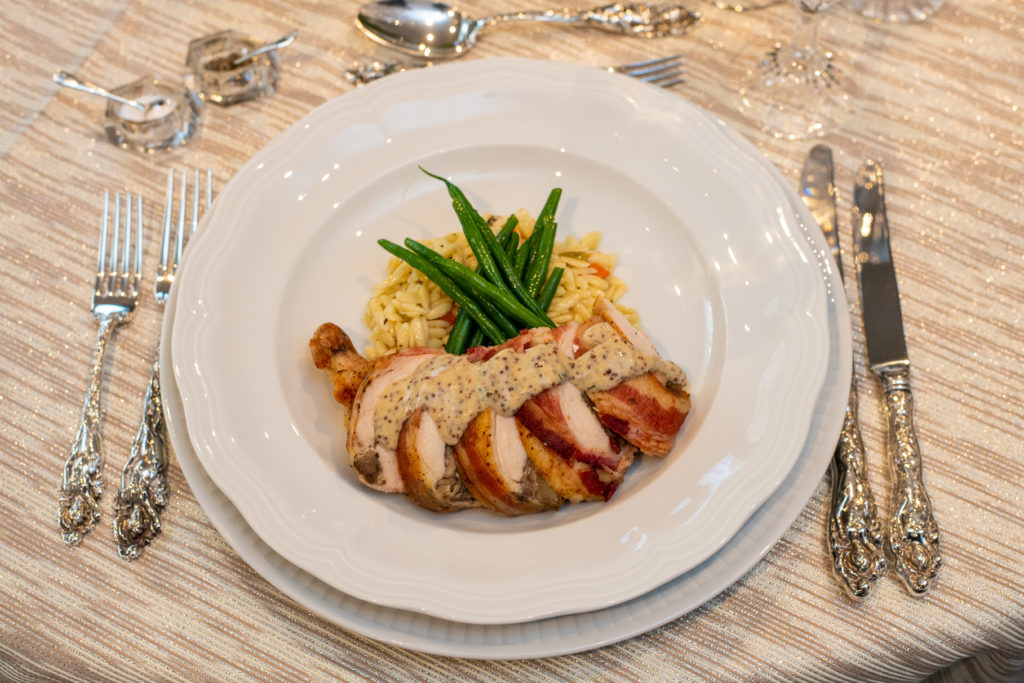 Bacon wrapped chicken breast stuffed with gruyère, mushroom and herbs, topped with Pommery mustard sauce, served with orzo pilaf and haricots verts and yeast rolls. (Photo by CatchLightGroup)