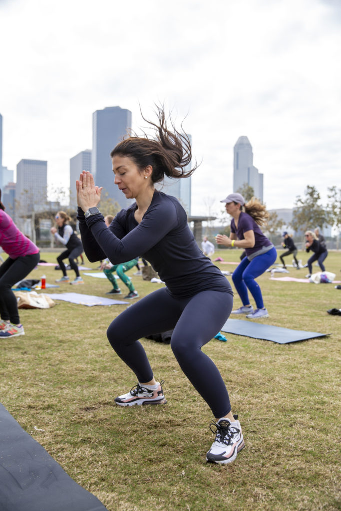 Nina Rand gets into the squats during the Savor + Sweat launch on the Brown Foundation Lawn at Buffalo Bayou Park. (Photo by Jenny Antill Clifton)