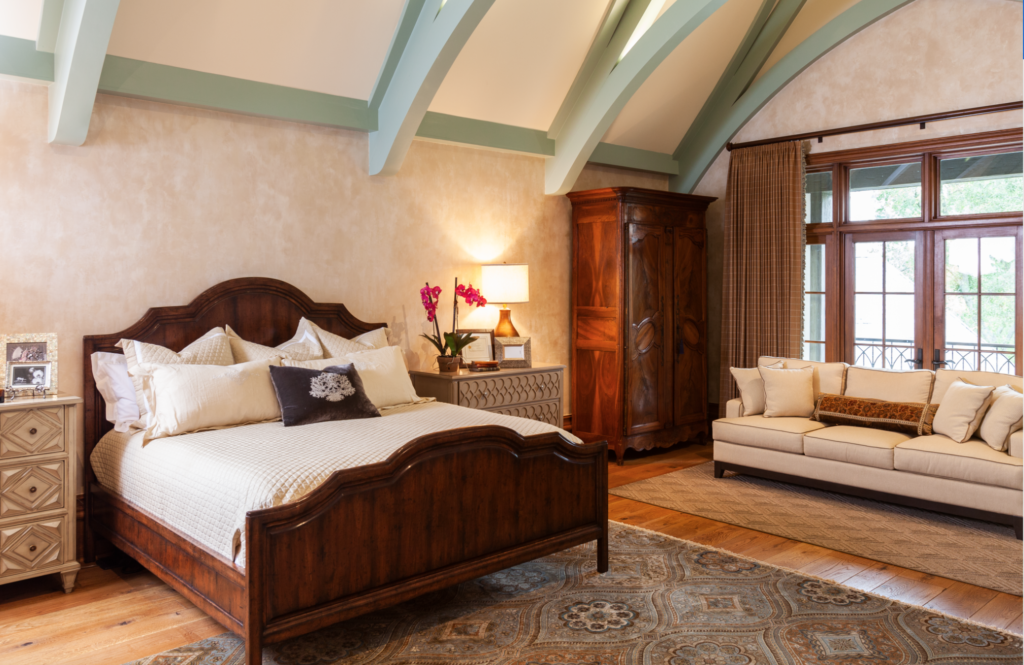 The primary suite is accented with soaring, 15 foot arched ceiling with flying buttresses, carved stone fireplace, and a private balcony. (Photo by Julie Soefer)