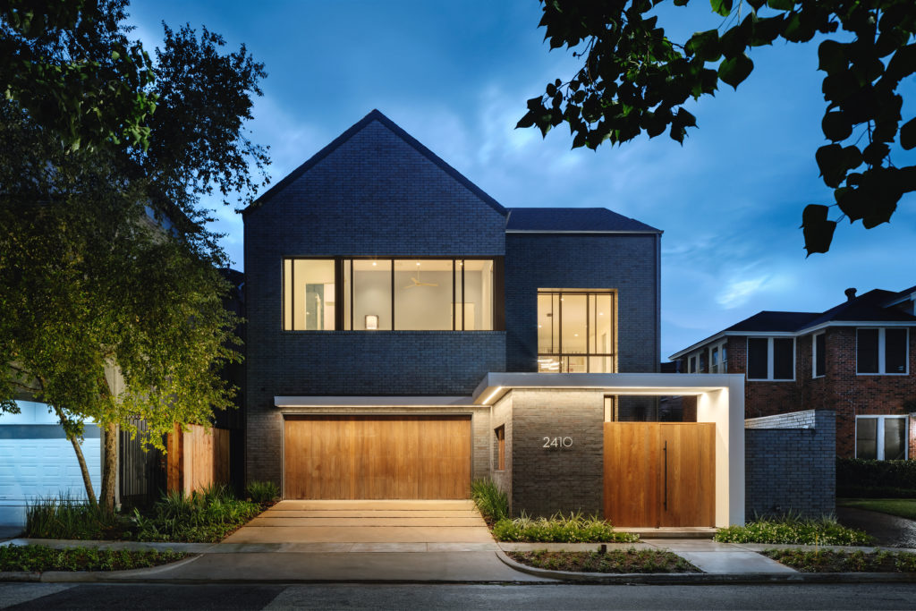 The traditional two-story single family residence with a simple gable roof projects urbane style living by incorporating contemporary materials such as the dark manganese brick.