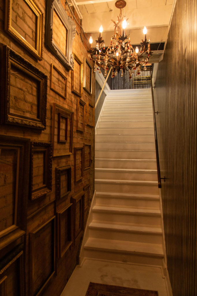 The art-lined stairway that leads to the second floor Volume Social Club salon. (Photo by Leah Wilson)