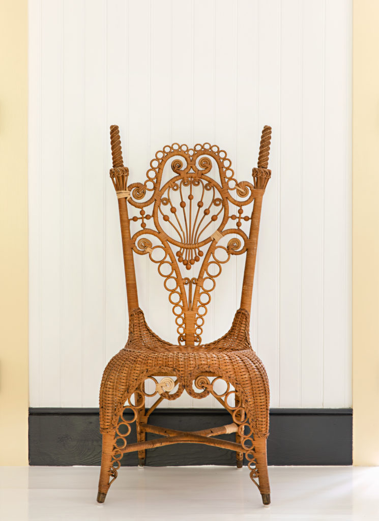 An antique wicker chair coiled into fiddlehead ferns.