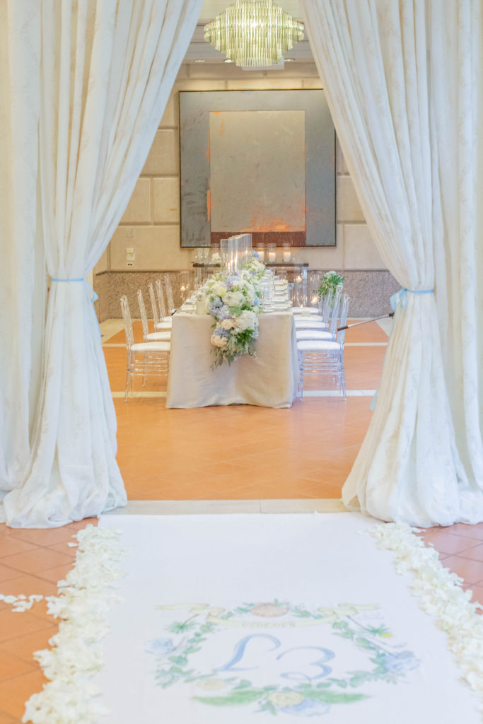 In the ceremony area, transformed by the Todd Events team, a beautiful runner emblazoned with their monogram led up to a stunning chuppah made from blue, white, and green hydrangeas. (Photo by Thisbe Grace McWilliams)
