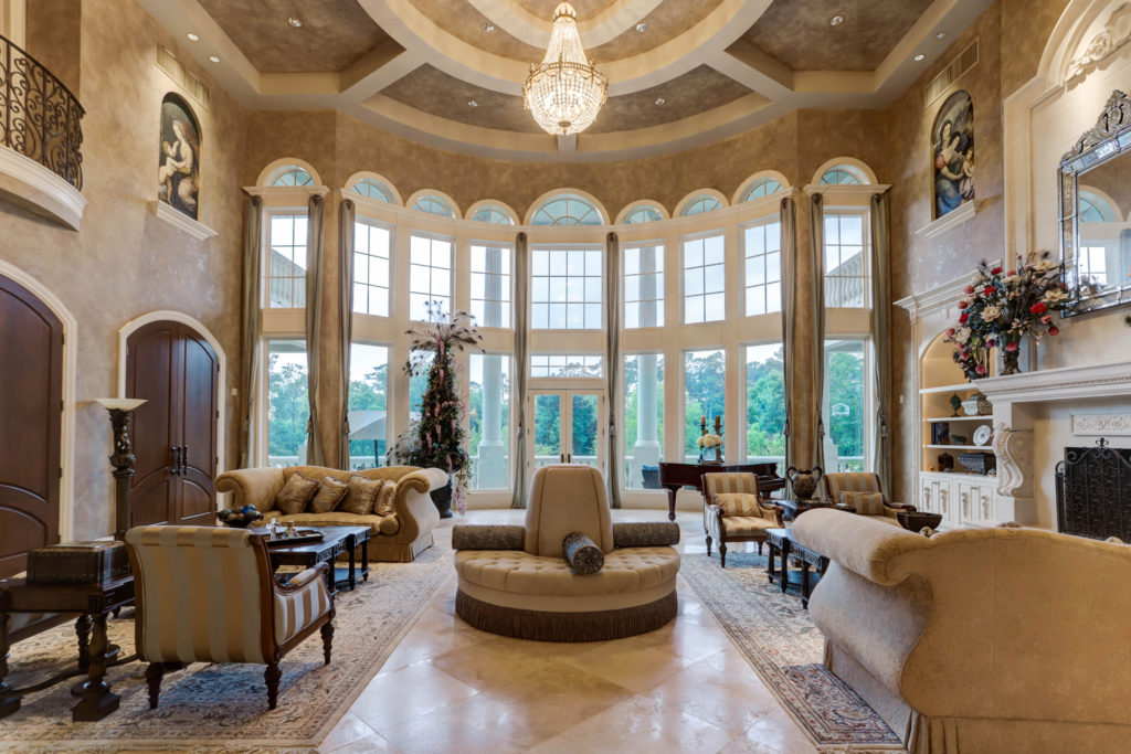 The double height living room offers a serene view of the grounds in the gated Kingwood community. (Photo by TK Images)