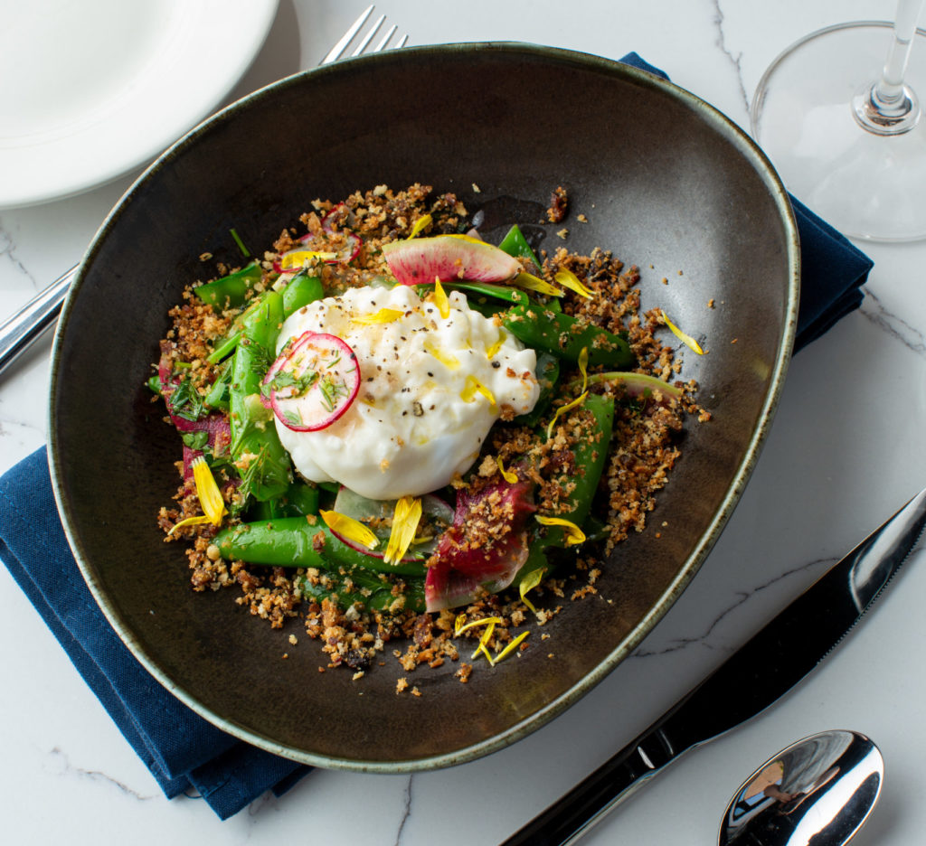 The spring pea salad at Roots Southern Table includes fresh burrata, radishes, and candied bacon. (Photo by Alyssa Vincent)