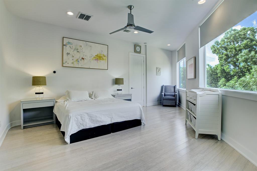 Windows in the second floor primary bedroom open to the treetops of the hike and bike trail.