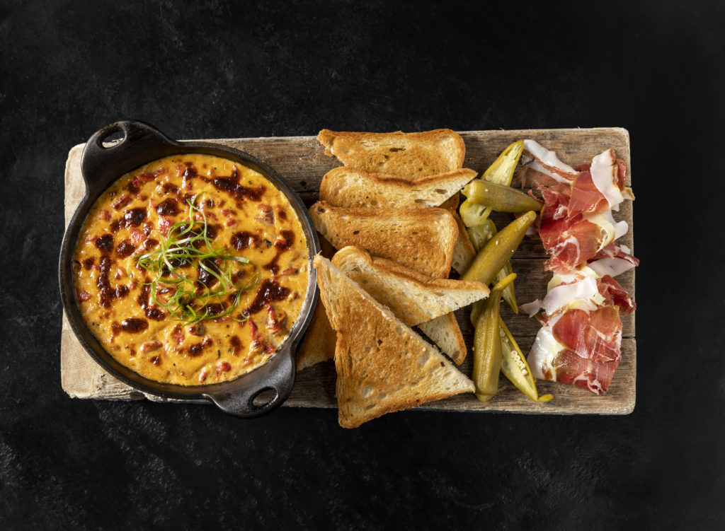 The baked pimento cheese with country ham, pickled okra and toast is one of the most popular dishes at Georgia James Tavern. (Photo by Julie Soefer)