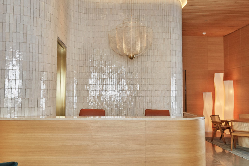 Concierge desk in white oak,
with handmade tile wall; Moooi
chandelier from Scott + Cooner. (Photo by Max Kutz)