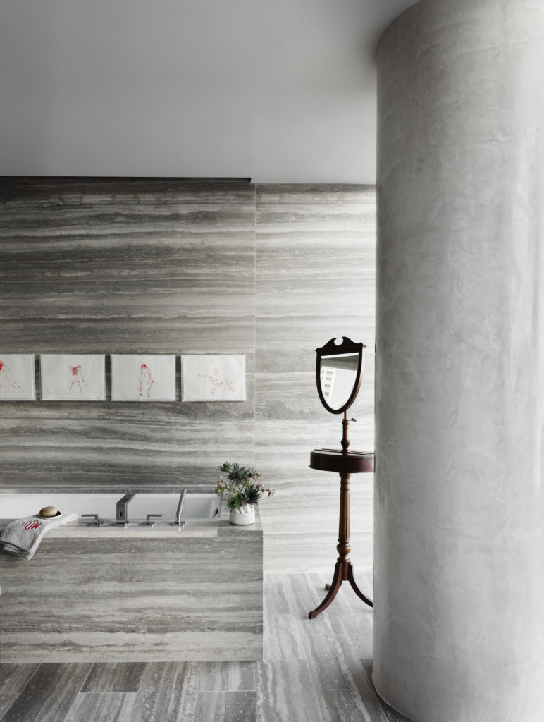 Waterworks Silver Cloud travertine clads floors and walls, in the main bath; Kohler tub. Dornbracht hardware. Tracey Emin monoprints. (Photo by Douglas Friedman)