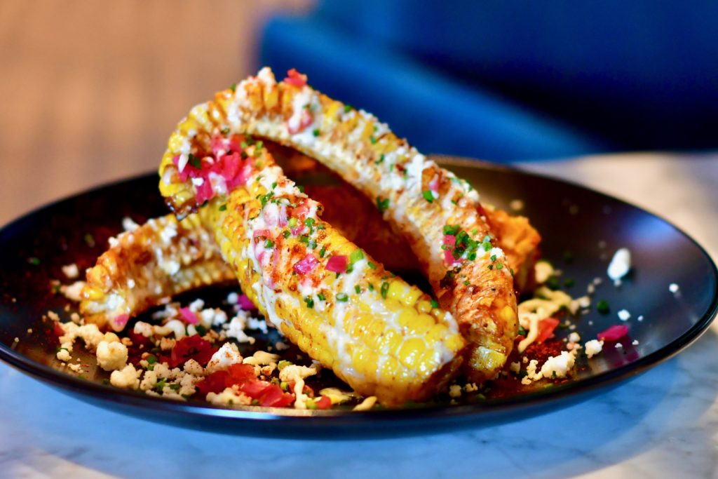 The elote ribs ($11) are covered with Mexican cheese, pickled onions and a butter crema, as well as spiced with the restaurant's signature spice mix. (Photo by Michael Anthony)