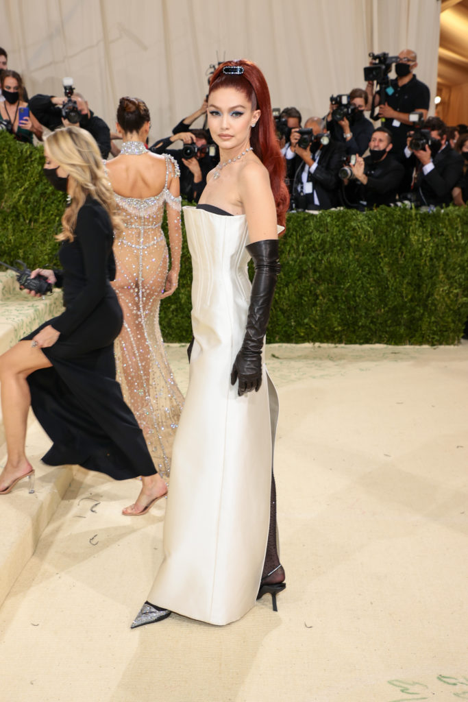 Gigi Hadid wears a Prada ivory silk radzimir gown with contrasting duchesse black bodice, characterized by a wide slit back and an exposed neckline paired with black beaded tights. (Photo by Dimitrios Kambouris/Getty Images for The Met Museum/Vogue )