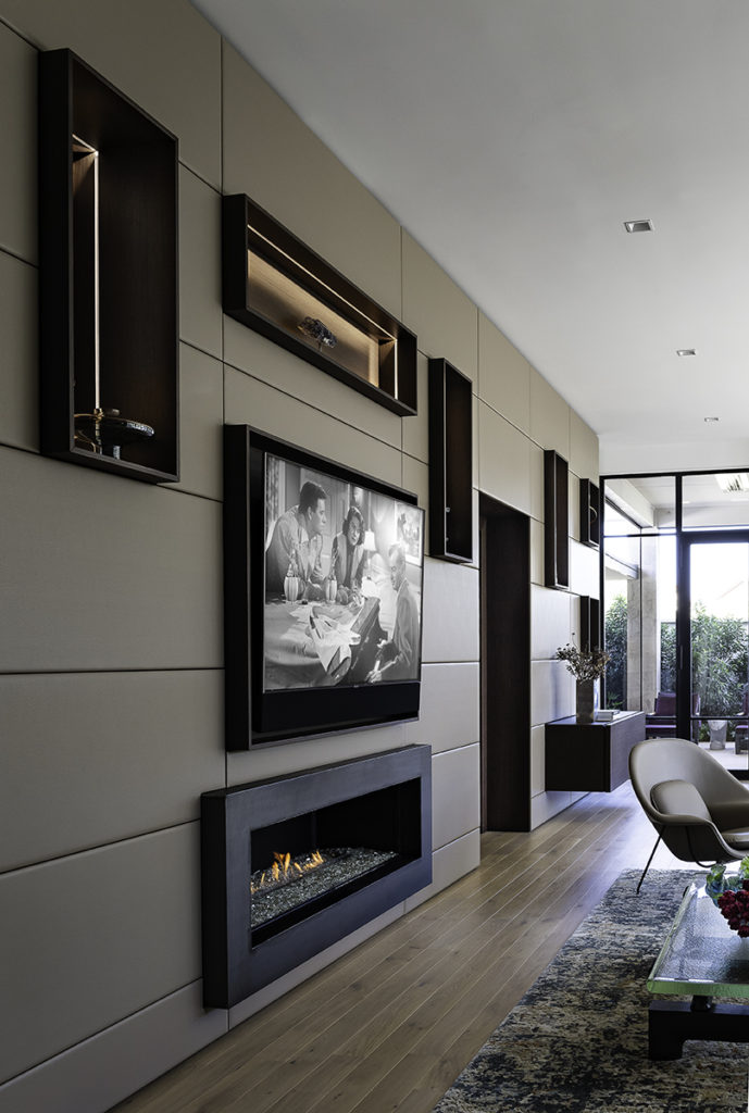 A cleverly installed wall of built-ins is also home to the living room's state-of-the-art Smart technology, tv, and fireplace.  (Photo by Manny Rodriguez)