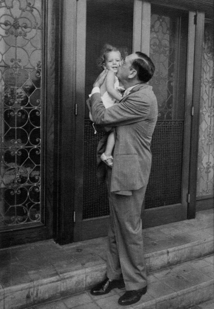 Herbert Marcus kisses 2-year-old granddaughter, Jerrie Marcus, on the steps of their Dallas house in 1938.