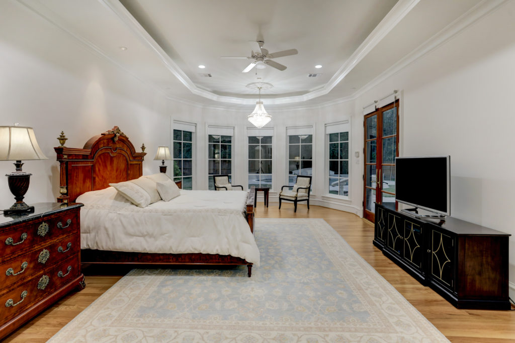 The primary bedroom at 6 Pine Tree Lane features new hardwood floors and French door access to the outdoor pool and patio. (Photo by TK Images)