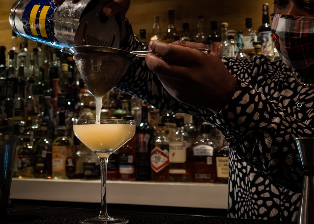 A bartender at The Usual prepares another craft cocktail to perfection.