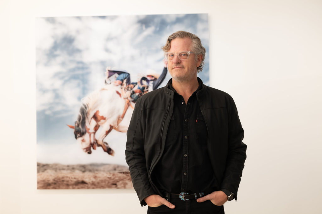 Photographer Steve Wrubel in front of one of his iconic rodeo photographs at the opening of artist Christopher Martin's gallery in the Upper Kirby District's Gallery Row in Houston. (Photo by Daniel Ortiz)