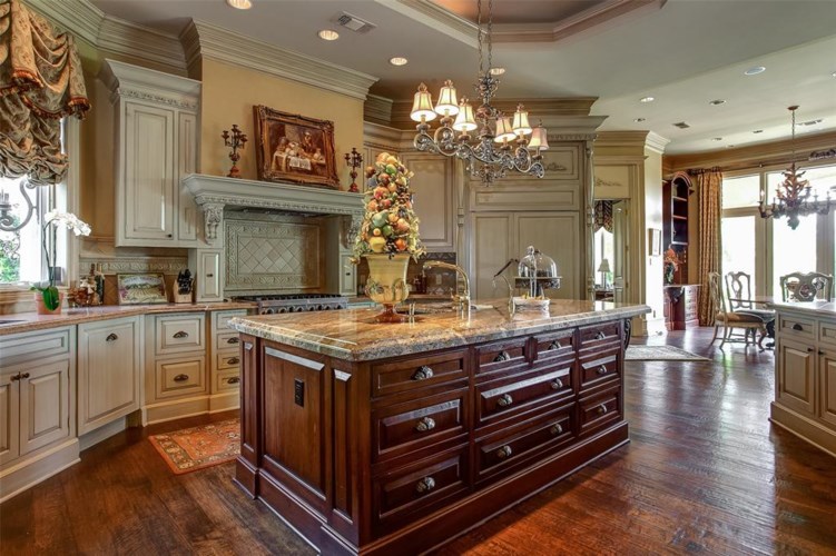Thick marble slabs and furniture style custom cabinetry in the dramatic kitchen.