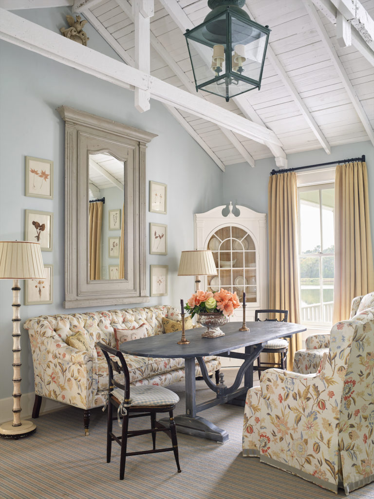 Ceiling beams inside Rose Cottage guest house were salvaged from old barns in the area and painted white. An old wine-tasting table serves as a place to eat, play cards or board games. Cozy sofa and chairs are upholstered in breezy, durable linen and cotton fabrics. (Photo by Tria Giovan)