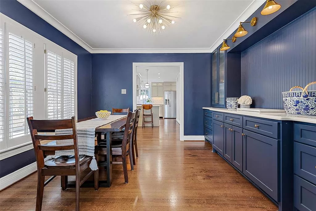 A handsome deep blue dining room with glamorous light fixtures. 