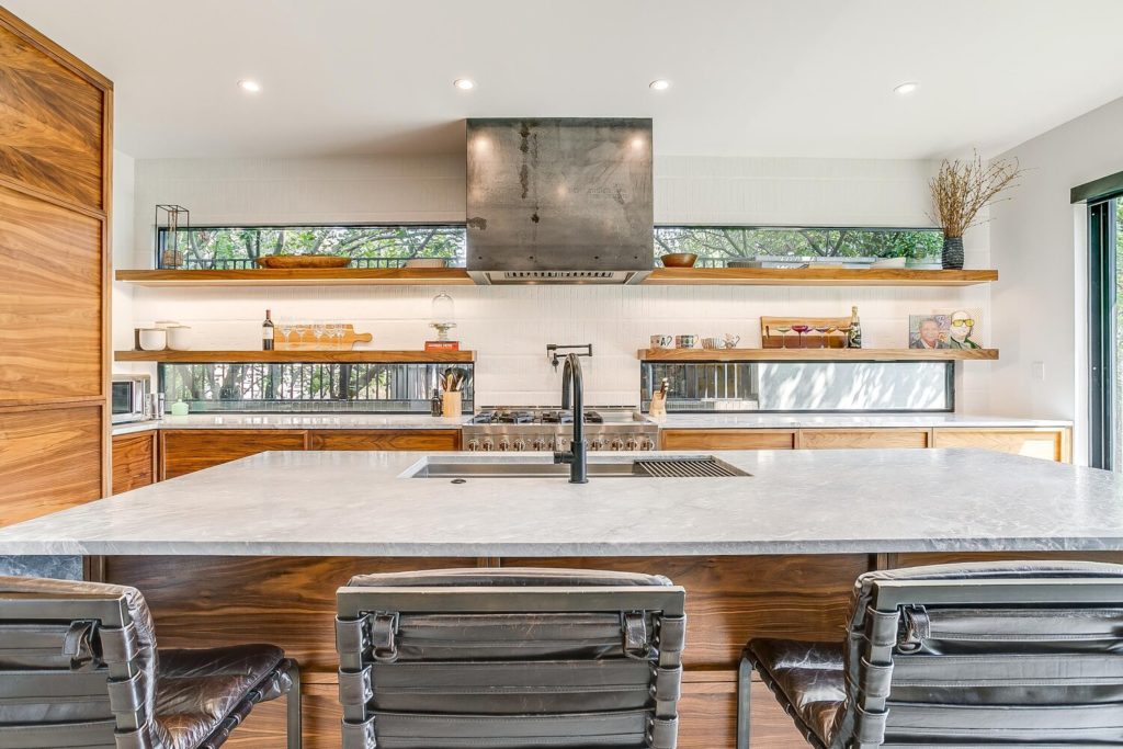 Rich walnut grain and leathered granite counters in the modern kitchen.