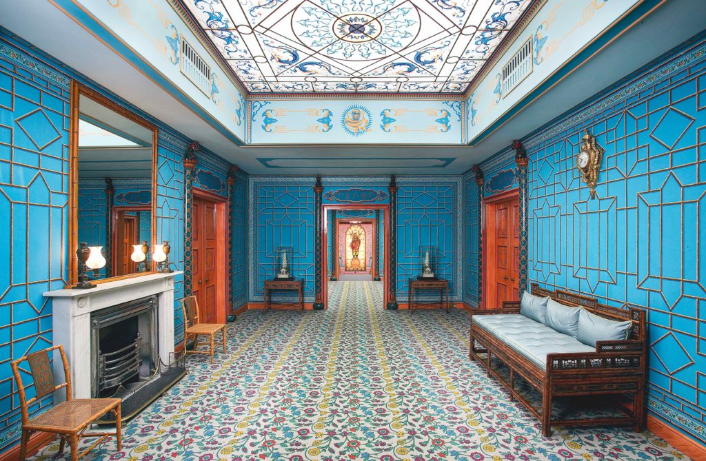 On the second floor of the Royal Pavilion, a double lobby links all the guest bedrooms. The faux-bamboo fretwork pattern on the vivid blue walls was inspired by the imported bamboo furniture.