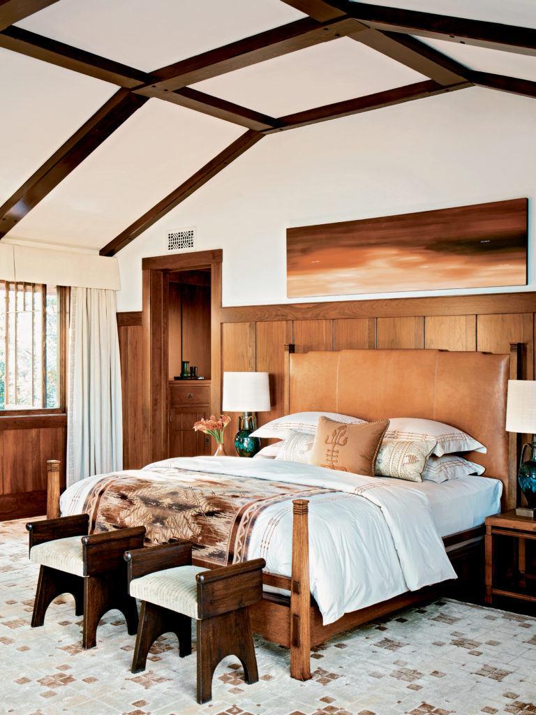Drapery panels in the master bedroom were embroidered with a pattern that, though not specifically Arts and Crafts in origin, feels appropriate to the period. Traditional Arts and Crafts joinery techniques were incorporated into this custom rift-oak-and-leather bed. The glazed ceramic lamps are the work of Christopher Dresser, an English designer of the nineteenth-century Aesthetic movement. The painting above the bed is by Ed Ruscha.
