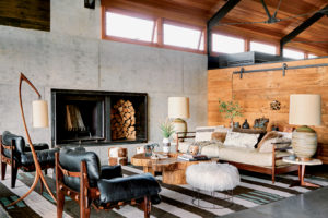 This house in Montana is essentially a single space divided into areas for living, cooking, and dining, with a screened-in porch at the far end. The retaining walls are board-form concrete, and the interior walls are a combination of reclaimed wood and Douglas fir.