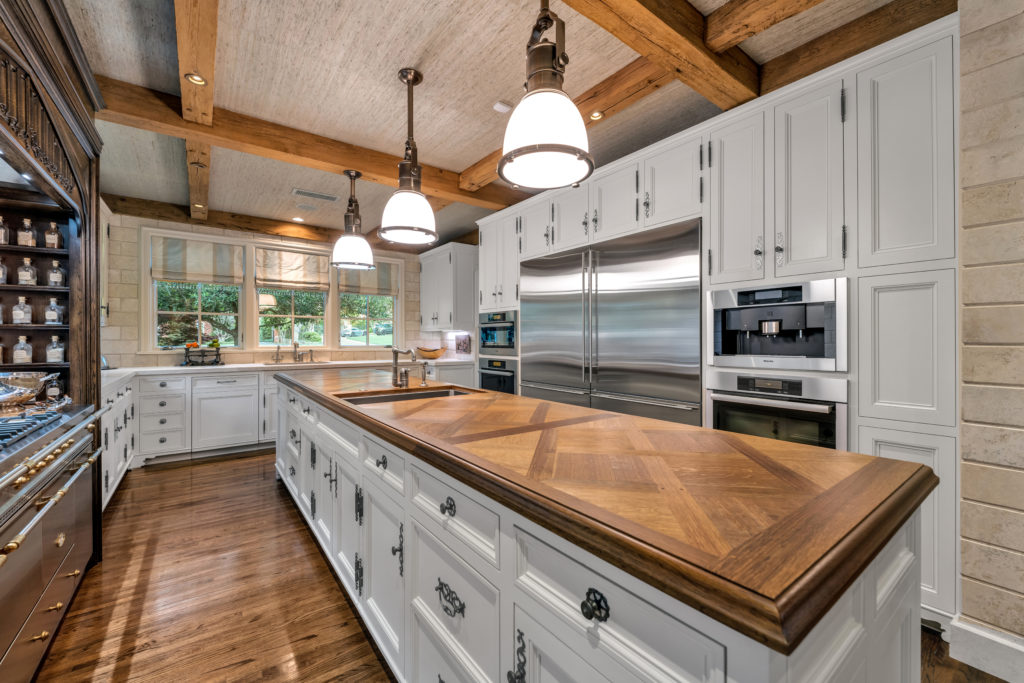 Parquet butcher block kitchen island with top name appliances and custom cabinetry in the kitchen.
