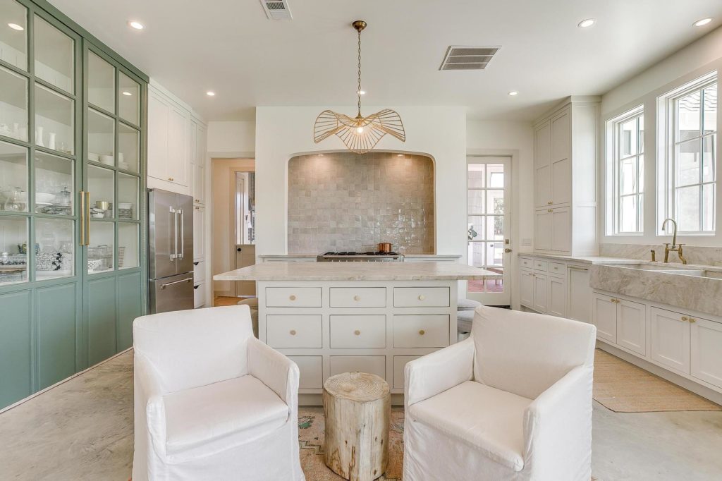 An open and inviting chef's kitchen fitted with Aga appliances and quartzite counters and sink.