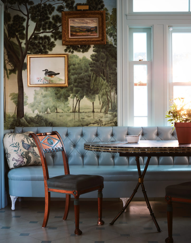 The breakfast room, with petite antique paintings and a custom leather banquette, is papered in one of Miles Redd’s favorite Iksel wallcoverings. (Photo by Trevor Tondro and Otto )