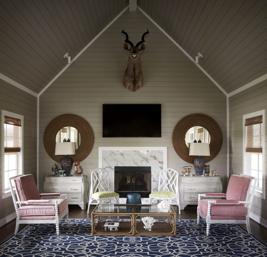 The great room of one of the three Red Antler bungalows has a Palm Beach vibe with a pair of pink velvet armchairs and rattan coffee table. Chinoiserie-inspired chairs from Memorial Antiques & Interiors, Houston. Rattan mirrors are an estate sale find. Kudo taxidermy mount from a South African safari where John Cone and his father were guests. (Photo by Pär Bengtsson)