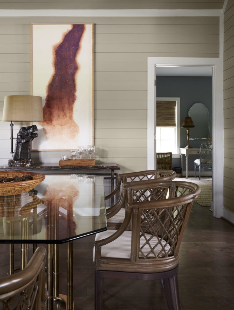 A dining room includes a Baldwin brass table from Memorial Traders, Houston and Safavieh rattan chairs. Lamp from Elizabeth Street Gallery, NYC is a cast bronze reproduction of an antique gargoyle. Painting by Texas artist, Liz Ward from Moody Gallery, Houston.