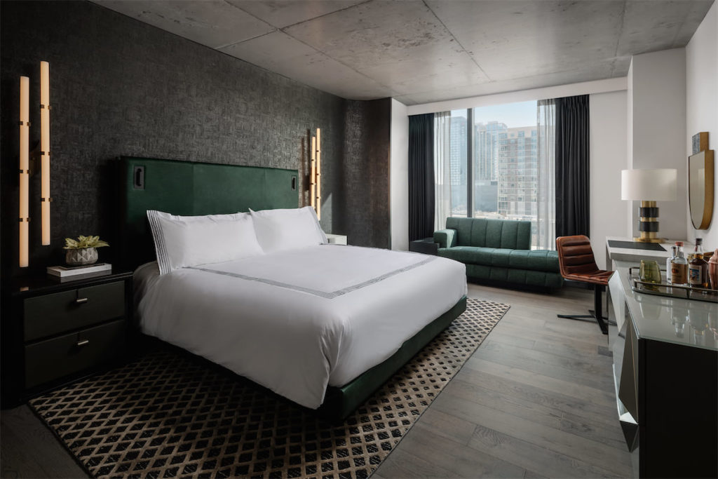 Thompson Austin guestrooms feature concrete ceilings, a black accent wall, and dark green leather headboard. (Photo by Chase Daniel)