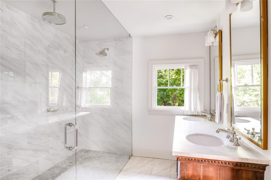 A frameless marble shower is surrounded by radiant heat flooring.