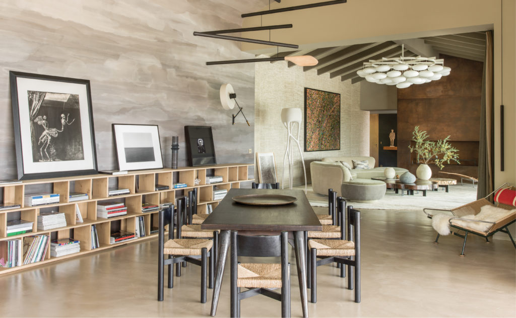  In a villa near Porto-Vecchio in Corsica, the dining room with living room in background designed by Jean-Louis Deniot. Chaise longue, PK24, in rattan by Poul Kjærholm. Plaster lamp by Charles Trevelyan from Carpenters Workshop Gallery. Hans Wagner chairs. Deniot commissioned Florence Girette to paint the vaulted ceiling inspired by the color of the local lauze stone, giving the space a more mineral feel. Jean Prouvé dining table and a mobile piece by French contemporary artist Xavier Veihlan that echoes the Oswald Haerdtl chandelier in the adjoining room. (Photo by Stephan Julliard)