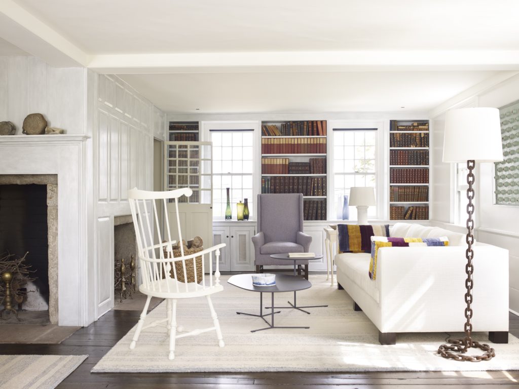 In an 18th-century New England saltbox cottage designed by Stephen Sills, familiar 18th-century furniture shapes that play well with the architecture are interpreted in a modern way: The wing chair with sharpened silhouette is a 1930s reproduction, and a Windsor chair receives a coat of white. (Photo by William Waldron)