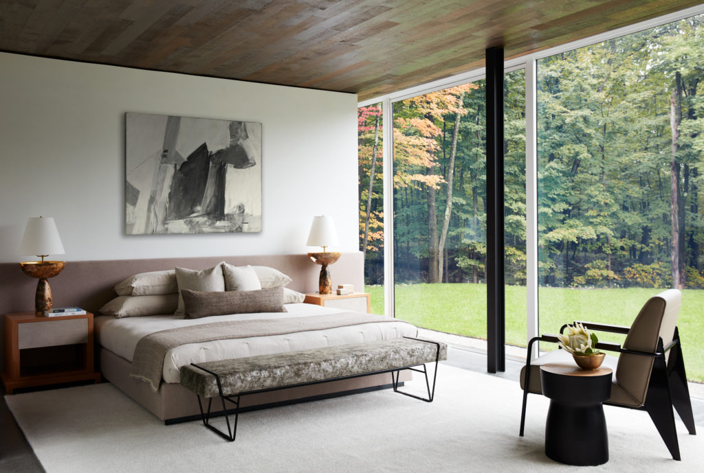 At a private oasis designed by Drake/Anderson in New York State’s Columbia County, the main bedroom and its adjoining bath are tranquil retreats, yet sumptuous in their appointments and in the way they both open directly into the landscape. The bed rests against a wall-to-wall upholstered headboard that creates a grounding horizon line. (Photo by Stephen Kent Johnson)