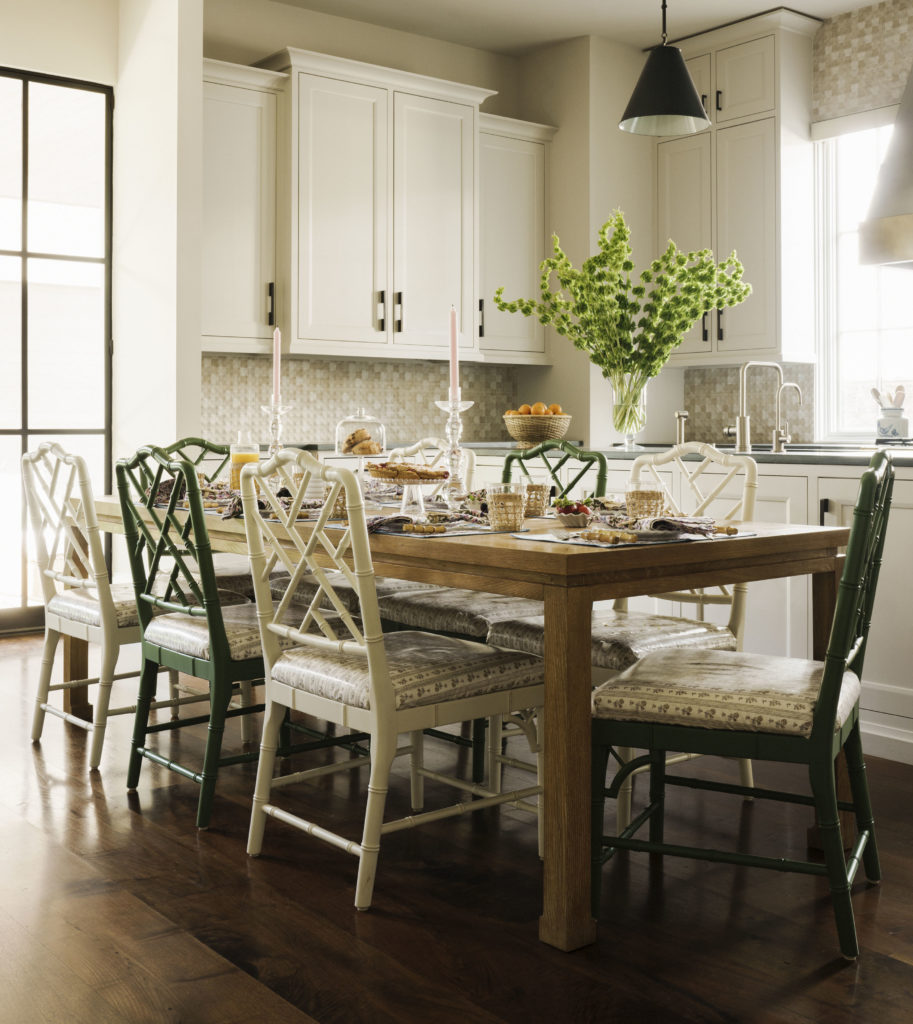 The kitchen table is surrounded by alternating green and cream painted upholstered lattice chairs for a playful touch. The kitchen backsplash is a warm geometric tile.  (Photo by Jack Thompson)