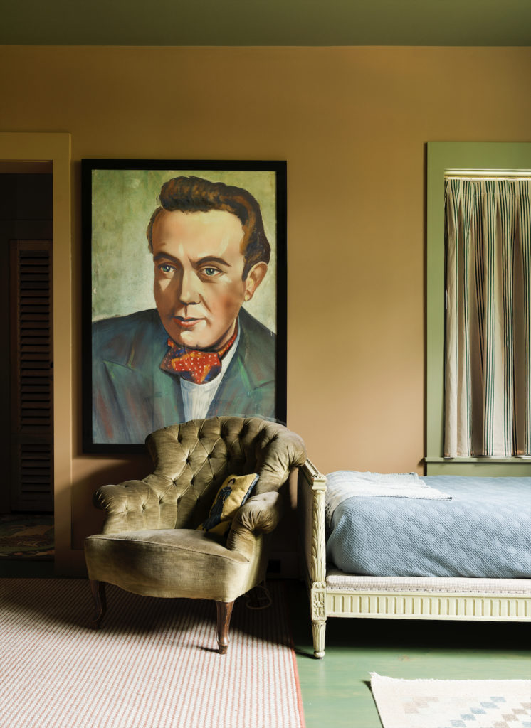 In a bedroom in Jill Brown’s farmhouse, vintage painting, chair, and bed were purchased in Belgium. Vintage rugs sourced by David Brantley. (Photo by Jack Thompson)