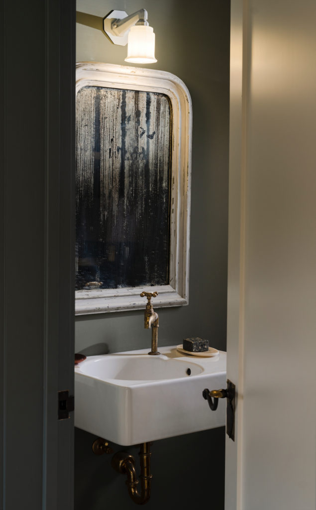 A guest bath with antique mirror from Belgium. Light fixture from Brown House and Wares. (Photo by Jack Thompson)