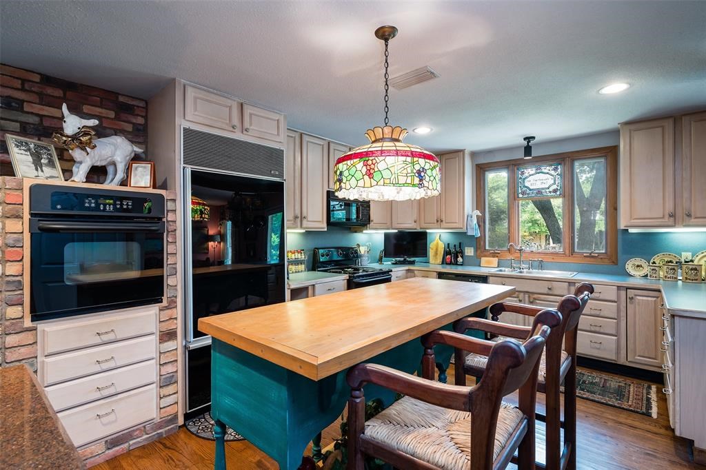 A sunny kitchen features a granite serving island. 