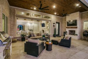 6025 Lakeside – the outdoor living space with full kitchen, and fireplace, afford a view of the the pool and lake.