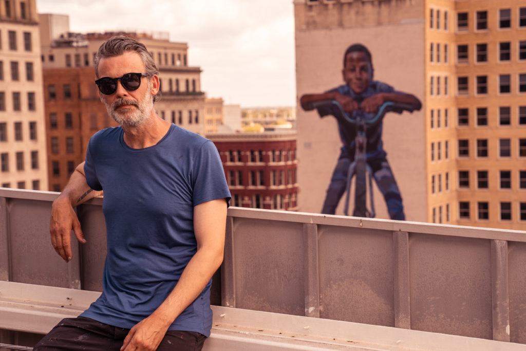 Case MaClaim stands in front of his mural, "Social Equity." (Photo by @superkant and @cyvisuals_, courtesy Street Art for Mankind)