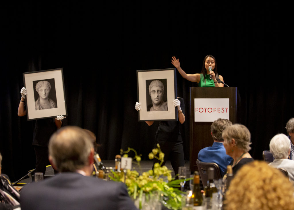Bonhams' Phyllis Kao auctions Diana Matar's "Tête à Tête, No. 46 Unidentified Portrait," (2019) and "Tête à Tête, No. 3 Unidentified Portrait," (2019) at the FotoFest Fine Print Auction (Photo by Tere Garcia)