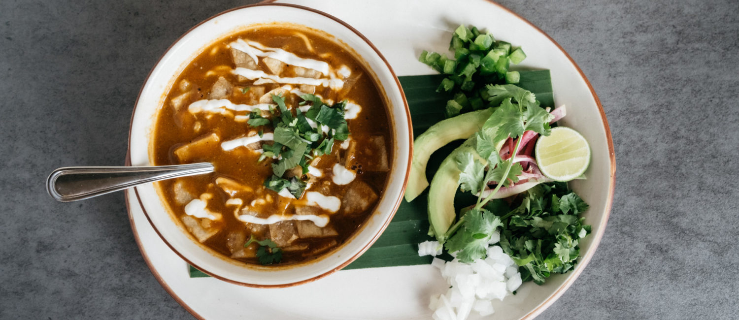 The chicken tortilla soup at Kitchen & Cantinia is made with red chiles and roasted chicken stock, hand-shredded chicken, avocado, cilantro and topped with traditional garnishes. (Photo by Caroline Fontenot)